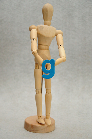 A wooden mannequin holding a letter gの写真素材