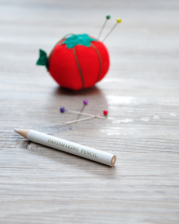 A dressmaker pencil with an out of focus pin cushion shaped as a red tomatoの写真素材