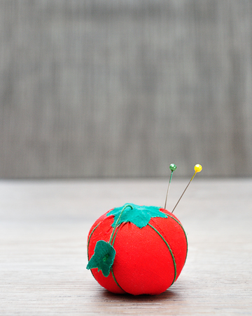 A pin cushion shaped as a red tomato with straight pinsの写真素材