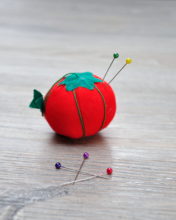A pin cushion shaped as a red tomato with straight pinsの写真素材