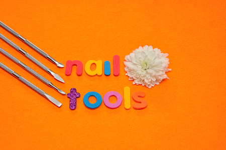 A set of nail tools and a white aster on an orange background and the word nail toolsの写真素材