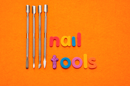 A set of nail tools on an orange background and the word nail toolsの写真素材