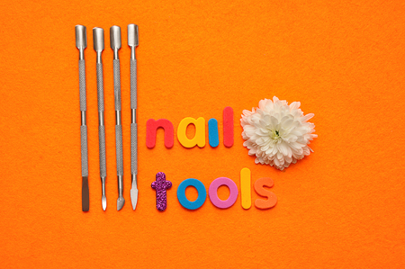 A set of nail tools and a white aster on an orange background and the word nail toolsの写真素材