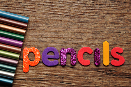 Coloring pencils with the word pencils on a wooden backgroundの写真素材