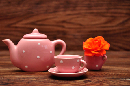A porcelain spotted tea cup and kettle and an orange roseの写真素材