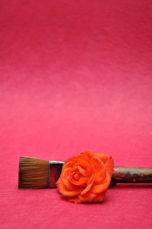 An orange rose with a paintbrush isolated on a pink backgroundの写真素材