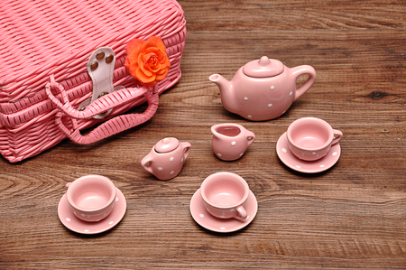 A porcelain spotted tea set with a pink basket and an orange roseの写真素材
