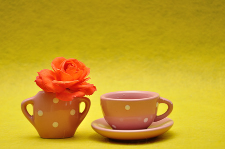 A teacup with an orange rose on a yellow backgroundの写真素材
