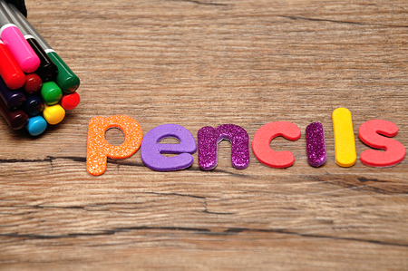 Coloring pencils with the word pencils on a wooden backgroundの写真素材