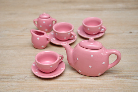 A set of spotted pink porcelain tea set on a wooden backgroundの写真素材