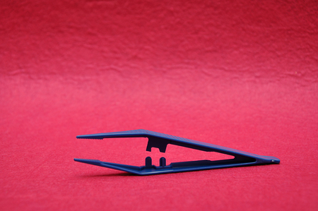A blue plastic tweezers isolated on a pink backgroundの写真素材