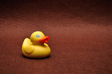 A rubber duck on a brown backgroundの写真素材