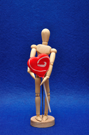 A wooden mannequin holding a heart shape lollipopの写真素材
