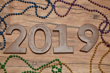 2019 in chocolate figures against a wooden background with colorful strings of beadsの写真素材