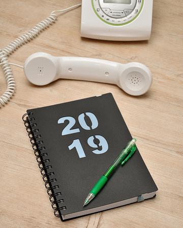 A diary for 2019, a pencil and a telephone on a wooden backgroundの写真素材