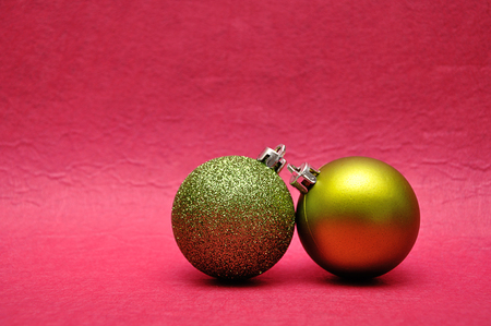 Two green Christmas tree baubles on a pink backgroundの写真素材