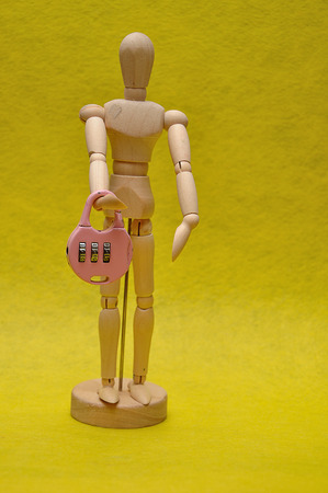 A wooden mannequin holding a combination padlockの写真素材