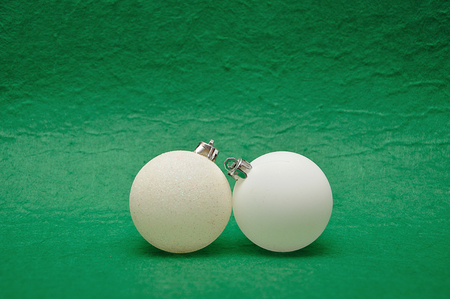 Two white Christmas tree baubles on a green backgroundの写真素材