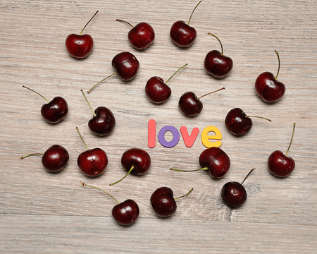 Cherries with the word love on a wooden backgroundの写真素材