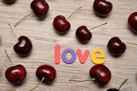 Cherries with the word love on a wooden backgroundの写真素材