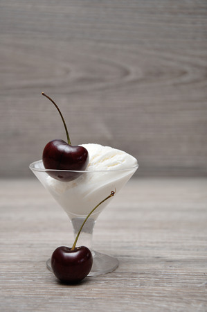 A single cherry on top of a scoop of ice cream in a glass bowlの写真素材
