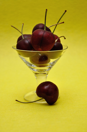 Cherries in a glass bowl with a yellow backgroundの写真素材