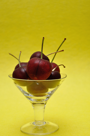 Cherries in a glass bowl with a yellow backgroundの写真素材