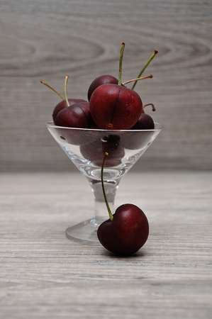 Cherries in a glass bowl with a wooden backgroundの写真素材