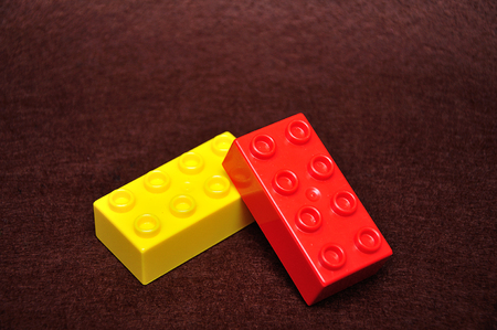 Two colorful building blocks isolated on a brown backgroundの写真素材