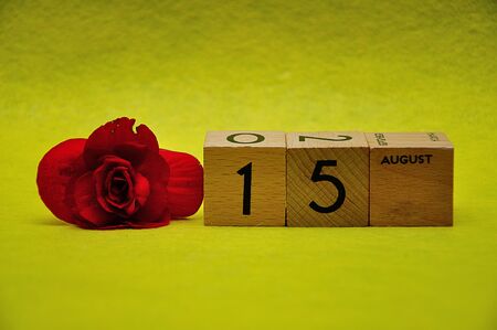 15 August on wooden blocks with a red flower on a yellow backgroundの写真素材