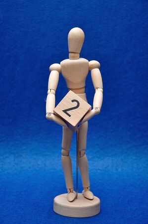 A wooden mannequin with a wooden block with the number twoの写真素材