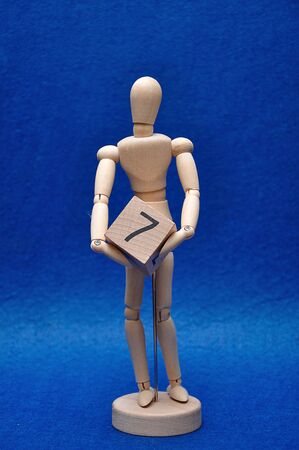 A wooden mannequin with a wooden block with the number sevenの写真素材