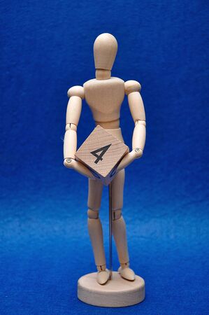 A wooden mannequin with a wooden block with the number fourの写真素材