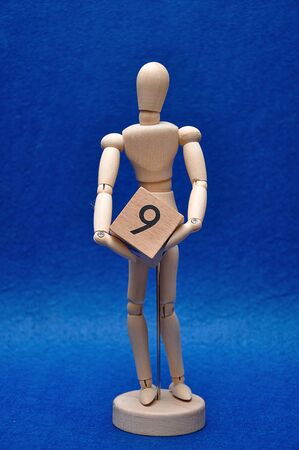A wooden mannequin with a wooden block with the number nineの写真素材
