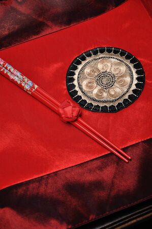 A pair of red chopsticks tied together on a red table clothの写真素材