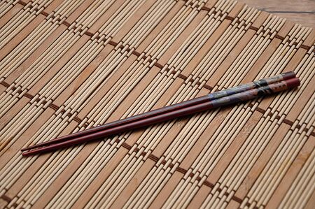 A pair of red chopsticks on a bamboo place matの写真素材