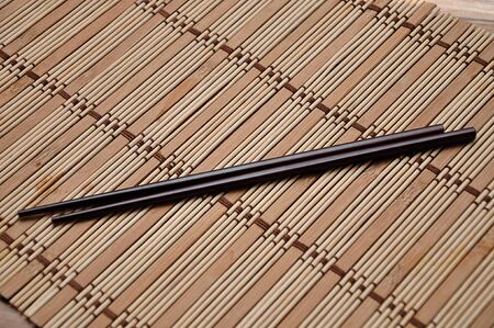 A pair of red chopsticks on a bamboo place matの写真素材