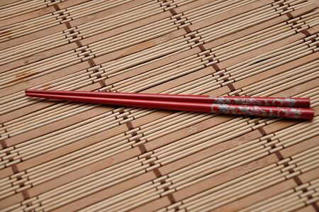 A pair of red chopsticks on a bamboo place matの写真素材