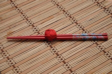 A pair of red chopsticks tied together on a bamboo place matの写真素材