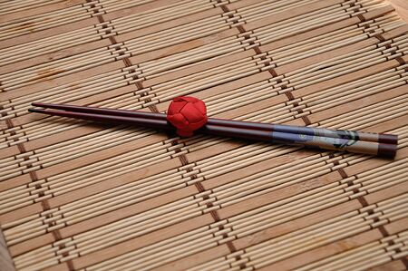 A pair of red chopsticks tied together on a bamboo place matの写真素材