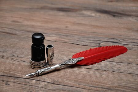 An old pen with a bottle of ink on a wooden tableの写真素材