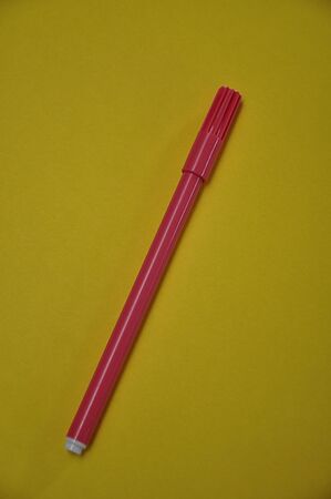 A pink pen isolated on a yellow backgroundの写真素材