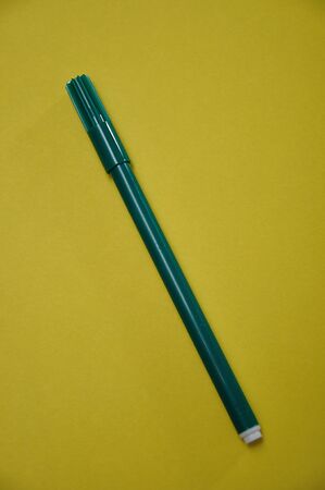 A green pen isolated on a yellow backgroundの写真素材