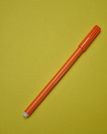 An orange pen isolated on a yellow backgroundの写真素材