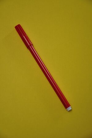 A red pen isolated on a yellow backgroundの写真素材