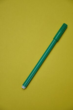 A green pen isolated on a yellow backgroundの写真素材