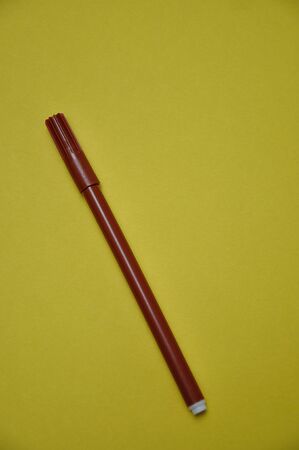 A brown pen isolated on a yellow backgroundの写真素材