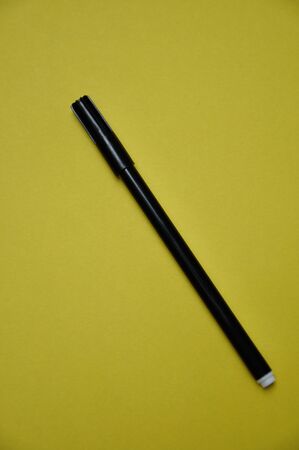 A black pen isolated on a yellow backgroundの写真素材