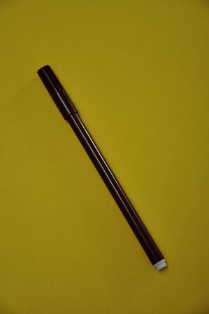 A brown pen isolated on a yellow backgroundの写真素材