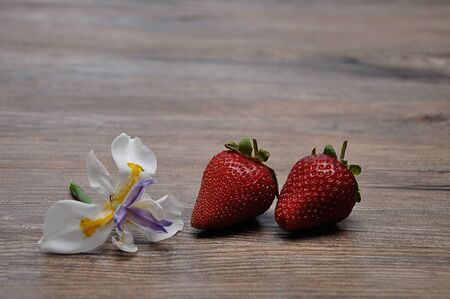 Strawberries displayed with an African Iris on a wooden backgroundの写真素材
